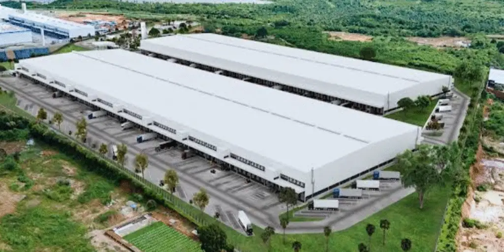 Imagem aérea de centro logístico de grande porte cercado por áreas verdes, com docas, caminhões e galpões amplos, ideal para operações de alta demanda